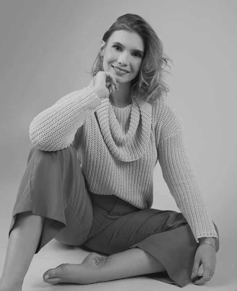 Foto da Neurologista Carol Alverez em momento de descontração sentada em Preto e branco a imagem